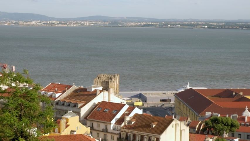 Pan across the Tagus River and Alfama to Praca Commercial. 