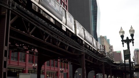 Day time exterior establishing shot of downtown Chicago office building facade outside of  track with slow moving train passing by during morning rush hour commute dx generic structure 4k video