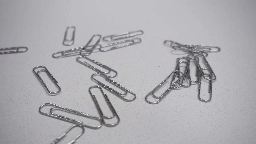 Metal clips fall on the table. Slow Motion 250FPS. Office concept.
