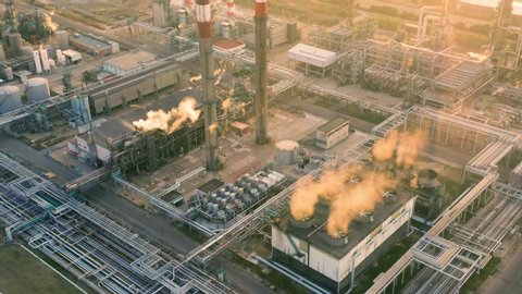 Aerial view of petrochemical oil refinery (refining complex) at sunset. Oil and gas tanks with smoking pipes on the plant (factory)