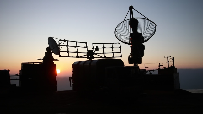 Creative artwork decoration. Silhouette of mobile air defence truck with radar antenna during sunset. Satellite dishes or radio antennas against evening sky. Selective focus | Shutterstock HD Video #1040798543