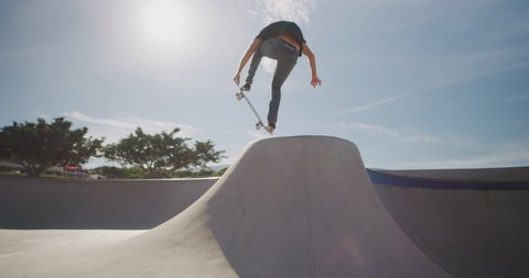 Skateboarder skateboarding in slow motion jumping out of a concrete bowl and over the over side, professional skateboarding tricks in slow motion