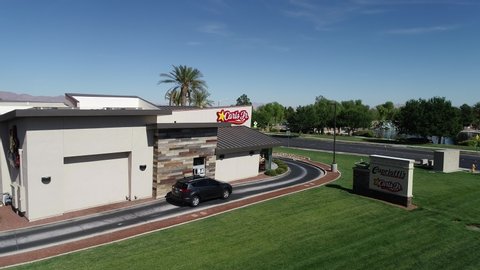 LAS VEGAS, NEVADA- SEPTEMBER 27, 2019: Carls jr sign on carls jr burger resturant building with black car in the drive throw, Drone view of Carls jr fast food resturant serving food in the drive in.