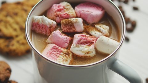 White mug filled with sweet cacao and marshmallows served on table with cookies and spices