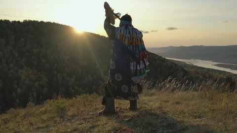 Ritual traditional dance with tambourine Siberian shaman at sunset.