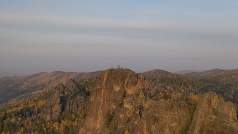 Aerial timelapse of high syenitic rocks in autumn forest at sunset.