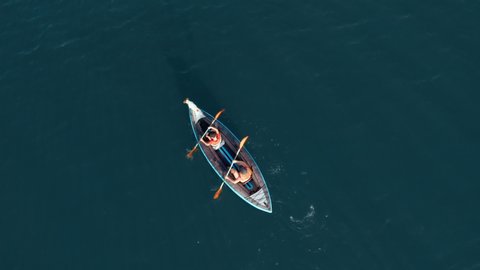 Aerial view drone happy mother and son rowing in inflatable kayak on water of large lake with dog on background of picturesque cliffs, green vegetation, beautiful sunset day. Family sport. Lifestyle