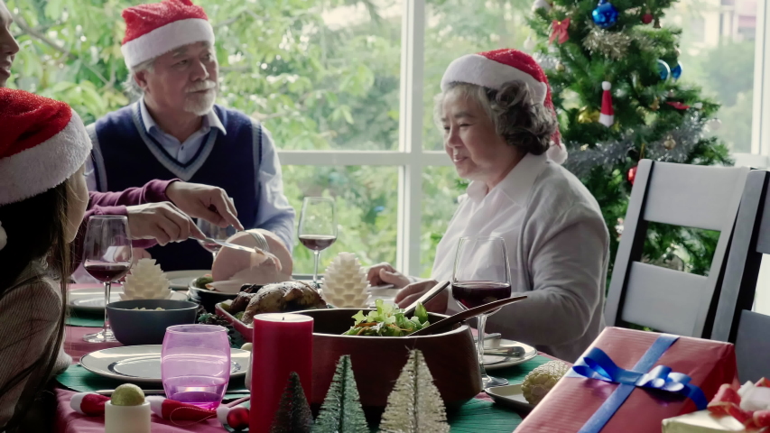 Asian family is eating for Thanksgiving. There are grandfathers, grandmothers, parents and daughter on the dinner table home. Celebrate Christmas and New Year. International family day. 4K Slow motion