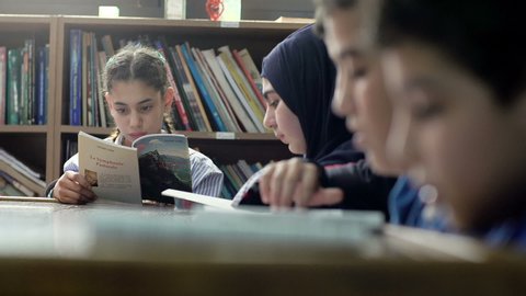 BEIRUT, LEBANON - 2016: Shift focus on students in 6th grade that read books at the school's library. Education in Lebanon is compulsory from age 6 to age 14