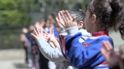 BEIRUT, LEBANON - 2016: Students in elementary school clap while cheering during sports contest at school's playground. Education in Lebanon is compulsory from age 6 to age 14