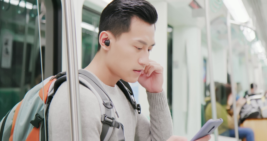 asian man use wireless earbuds to listen music or watch video on the metro Royalty-Free Stock Footage #1040827259
