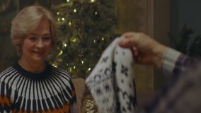 Senior adult Caucasian couple exchanging gifts on Christmas Eve at their home, old man receiving a sweater from his wife. Shot on ARRI Alexa Mini with 2x Cooke Anamorphic lenses. 4K UHD RAW Graded foo - Powered by Shutterstock - Get 15% off with code: PIKWIZARD15