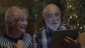 Senior adult Caucasian couple having a video call with their friends or family on Christmas Eve at their home. Shot on ARRI Alexa Mini with 2x Cooke Anamorphic lenses. 4K UHD RAW Graded footage