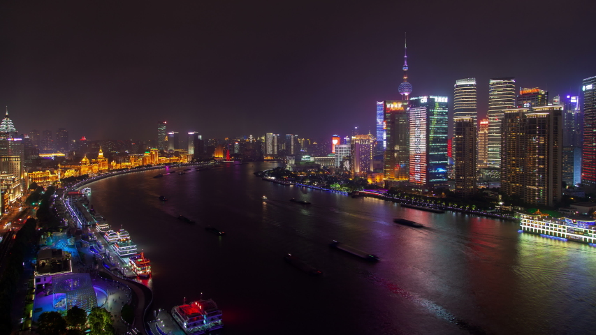 Timelapse modern Shanghai buildings and skyscrapers with bright coloured advertisement illumination on Chinese Huangpu river bank at night