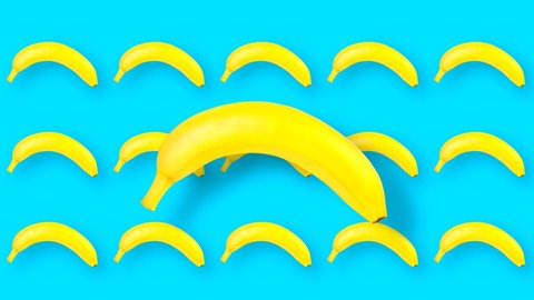 Animated looped film with moving and rotating fruits close-up and finely. Photo of a whole banana in motion on a blue uniform tone.