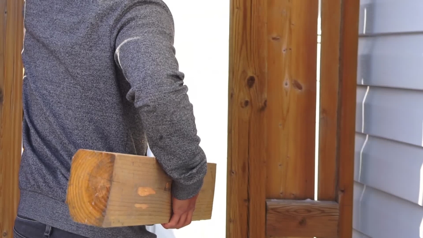 Man carrying piece of timer into his garage 