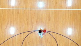 Drone view of basketball player dribbling and running down court with wood floor.