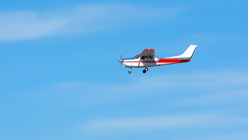 Generic Small Private Single Engine Airplane Flying in a Sunny Blue Sky with Thin White Clouds