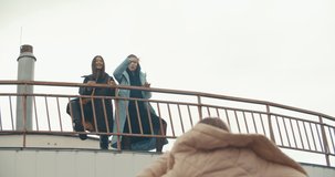 Young attractive women wearing black coat with hood standing at rooftop of parking at city center. Pretty naughty arabian and caucasian fashion girls friends . 4k raw video slow motion 60 fps