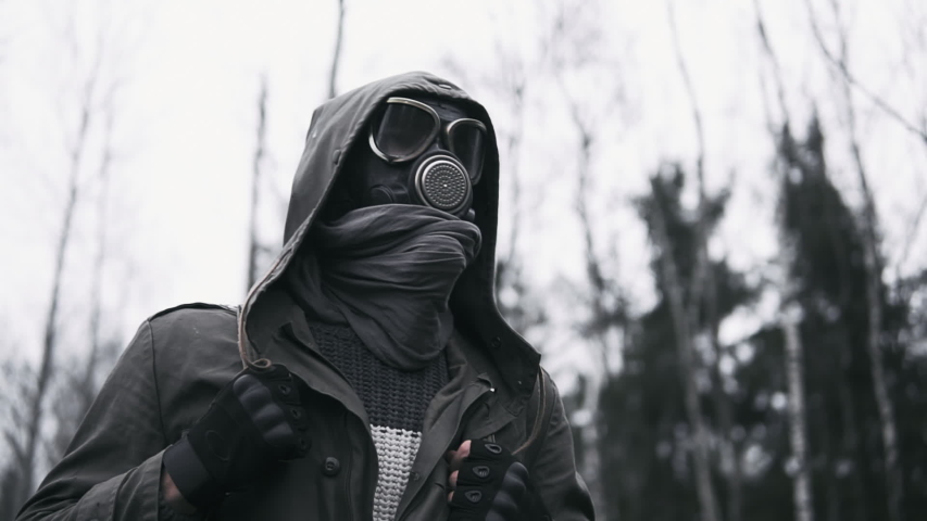Male wanderer in protective gas mask walking in empty dark forest. Stalker concept, portrait of lonely survivor after nuclear or chemical war. Post apocalyptic world. Stedicam following shot | Shutterstock HD Video #1040861873
