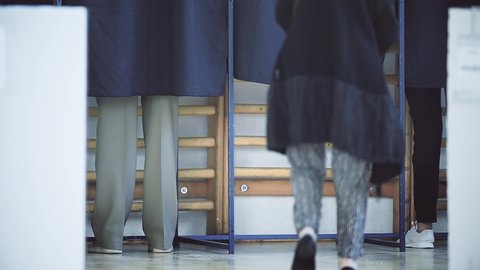 Unrecognizable people casting their votes inside voting booths during elections	