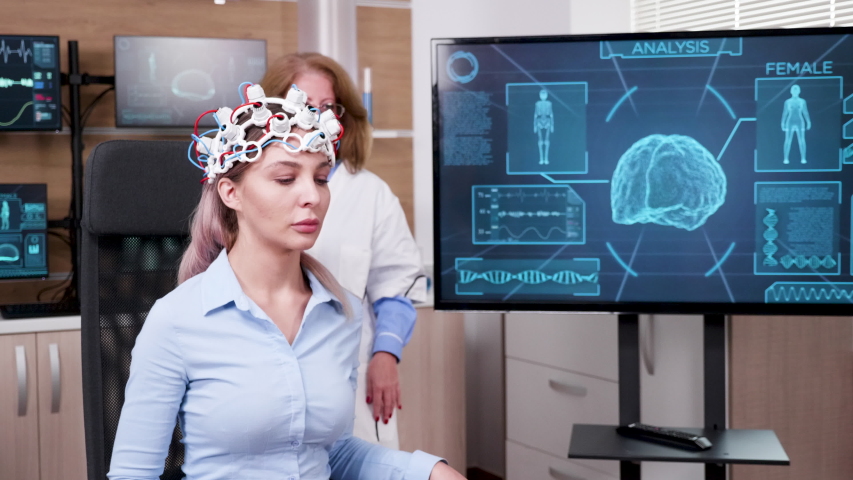 Female doctor in brain science lookin at tv screen to see patient neuronal activity.