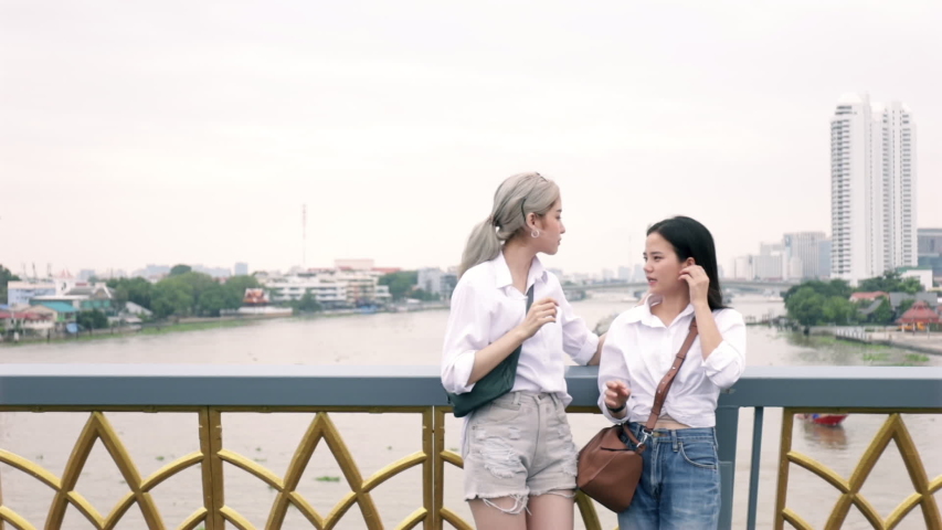 Asian lesbian couples enjoying traveling and talk while standing on the bridge. LGBT concept.