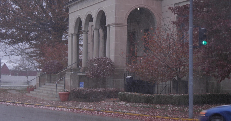 A morning snowy establishing shot of the Laughlin Memorial Public Library in Ambridge, Pennsylvania as traffic passes by. Pittsburgh suburbs.  	