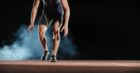 Asian athlete having an evening training, putting himself on starting position, then blasting off and sprinting, isolated on black background- sports concept 4k footage