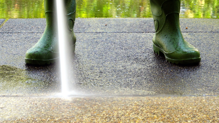 Worker cleaning dirty floor with high pressure washer splashing the dirt ,4K timelapse .
High pressure cleaning ,lower body with waterproof boots.
Professional cleaning services.