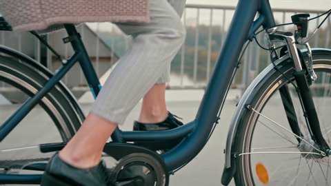 Close up Female Feet in Casual Shoes Cycling in City on Bridge in the Autumn Morning. Urban Cycle Chic and Ecological Transportation by Bike. 4K Close up Low Angle Tracking Shot