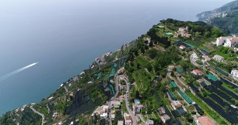 Aerial drone flight view of Ravello town at green mountains top on seashore. Houses and buildings of village in forest on rocks. Sunny summer day Italy Amalfi Coast Amalfitana Blue clear sky