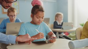 Elementary School Computer Science Class: Smart Boy Uses Laptop Computer, Friendly Teacher Helps Him by Explaining Lesson. Children Getting Modern Education in STEM, Playing and Learning - Powered by Shutterstock - Get 15% off with code: PIKWIZARD15