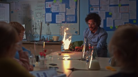 Elementary School Chemistry Classroom: Engrossed Children Watch How Enthusiastic Teacher Shows Science Experiment by Setting Powder on Fire Creating Beautiful Fireworks. Kids Getting Modern Education