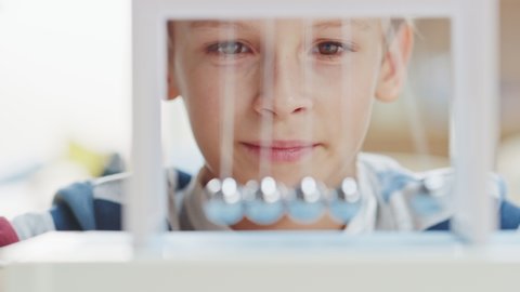 Close-up Portrait of an Inquisitive Young Boy Looking at Newton's Cradle. Child Learning about Physics