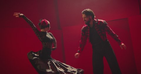4K Beautiful couple dancing latin dance . Professional dancers dancing flamenco, rumba or salsa on red background. Pair in spanish dress performs dance movement. Shot ARRI ALEXA Camera in Slow Motion