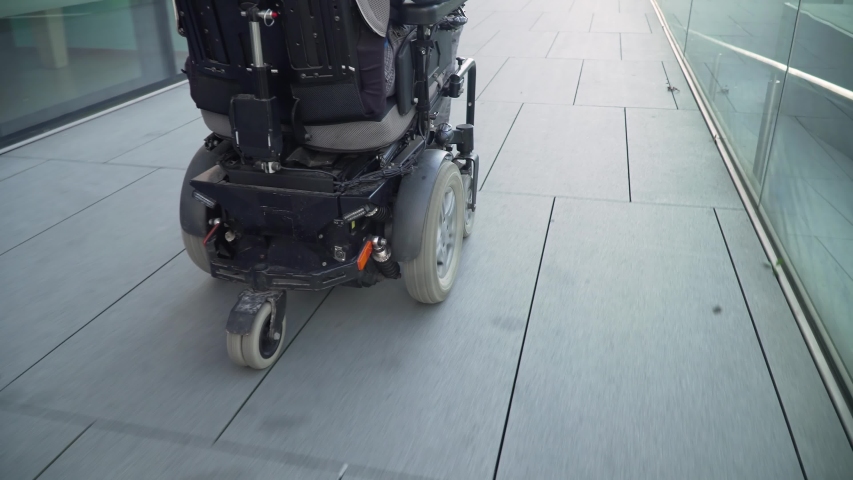 4k resolution closeup follow from a back of a man with a disability on electric wheelchair driving on a street. Accessibility concept Royalty-Free Stock Footage #1040922125