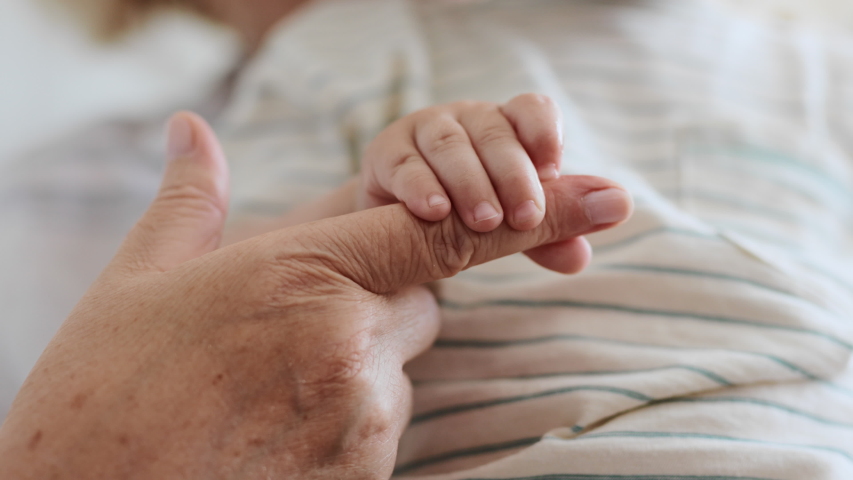 Family Relation of Elder Grandmother and Happy Grandchild. Hand of Carefree Son Holding Finger of Caucasian 60s Woman. Happiness of Parent and Newborn Baby at Comfortable Home in Day Lighting Indoors Royalty-Free Stock Footage #1040924696