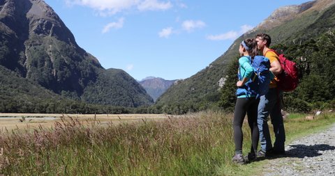 New Zealand hikers backpackers tramping on Routeburn Track, famous trail in the South Island of New Zealand. Couple looking at nature landscape. Fiordland & Mount Aspiring National Park, New Zealand
