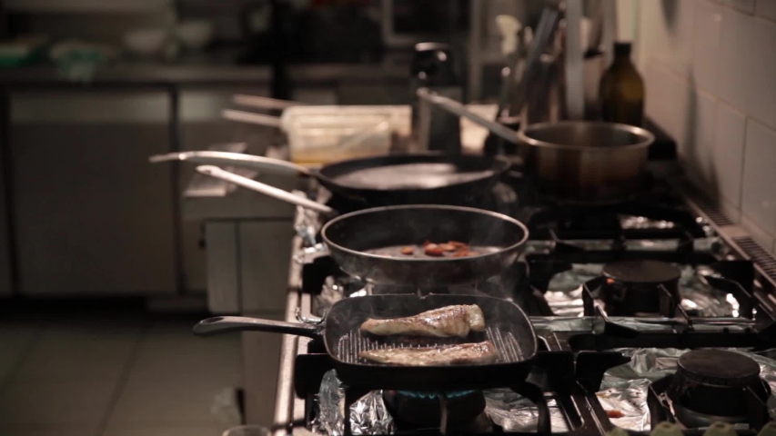 Lockdown midsection of chef cooking meat on stove in commercial kitchen