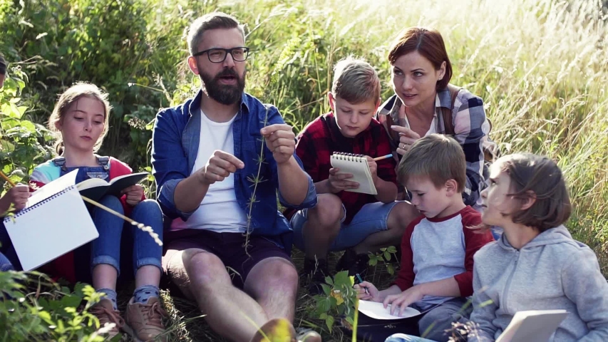 Group of school children with teacher on field trip in nature. Slow motion.