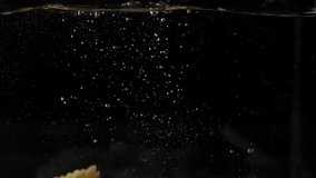 Pasta fusilli falling in water, slow motion video. 