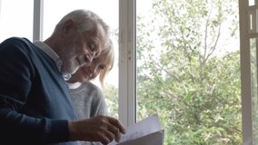 senior elderly Caucasian man and woman read script briefing document paper together near window in bedroom, retirement lifestyle concept - Powered by Shutterstock - Get 15% off with code: PIKWIZARD15