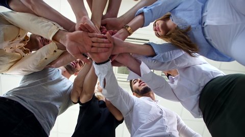 Company of young employees Low Angle View Stacking Hands Together in office