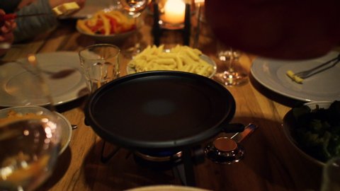 a family enjoying cheese fondue and they stick bread in the melted cheese in a chalet or lodge setting	