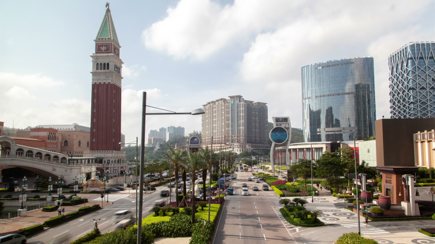 Timelapse cars drive along wide Cotai road between Macau New Urban Zone buildings of Istmo street with large red white Venetian tower in China