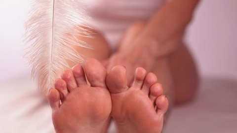 Closeup woman tickles her soft toes with feather. Foot care