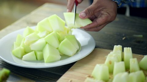 Chef sliced fresh sweet green melon and cut to small pieces put on white dish on wooden table.Slice to pieces of melon for easy eat and can make melon juice.Honeydew melon, also known as a honeymelon.