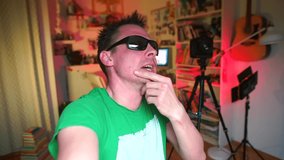 Drunken video blogger in sunglasses talks about nightclub party. Holds camera, gestures hand. 
Alcoholism in home isolation due to covid-19 quarantine lockdown. Drinking in coronavirus self-isolation.