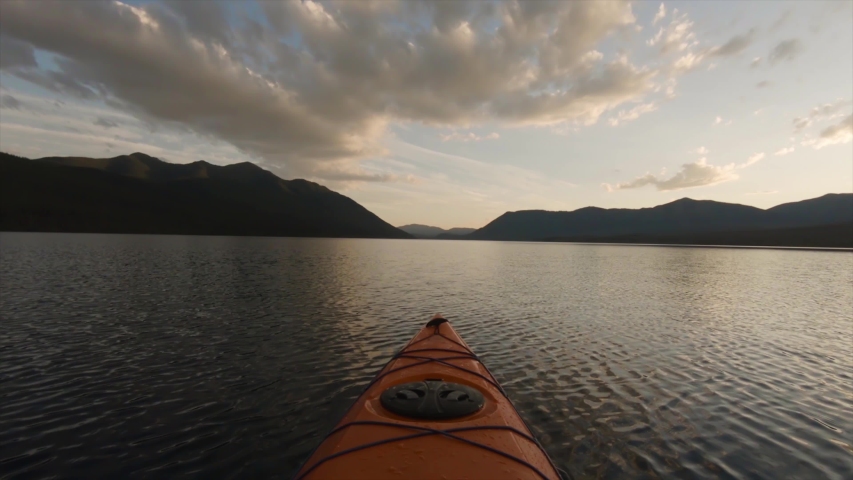 Kayaking in Glacier Lake surrounded by the beautiful Canadian Rocky Mountains during a cloudy summer sunset. Taken in Upper Waterton Lake, Alberta, Canada.